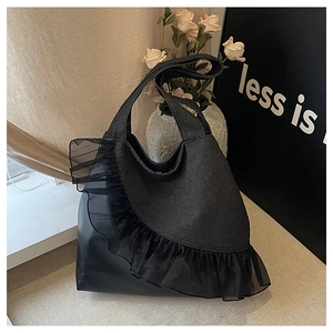 Detail of the black tote bag featuring lace mesh ruffle trim and contrast fabric textures