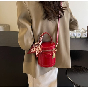 Detail of red cylinder handbag with silk scarf handle and golden lock charms