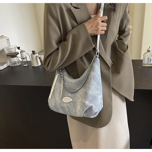 Hellblaue Denim-Hobo-Tasche mit Silberkette, getragen von einem Modell im Café-Stil