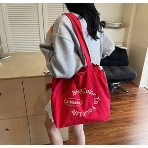 Detail of red canvas tote bag featuring white slogan print and drawstring closure design