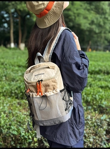 Close-up of khaki outdoor backpack featuring orange zipper pulls and mesh side pocket