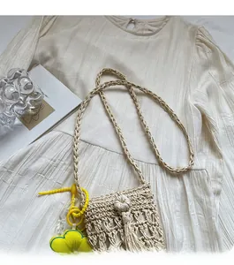 Dettaglio della borsa in paglia beige intrecciata a mano con ciondolo a fiore
