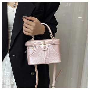 Detail of light pink pearl finish denim box bag with gold rivets and top handle