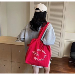Red large capacity canvas tote bag shown on model shoulder for daily commute size reference