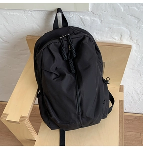 Close-up of black waterproof backpack featuring a unique vertical zipper with woven cord puller