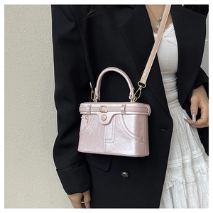 Detail of pink glossy patent leather box bag with gold studs and cross-body strap
