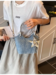 Light blue textured bucket bag with silver handles and star charm shown as crossbody style