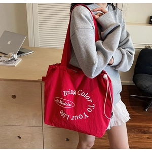 Detail of red canvas tote bag with adjustable drawstring and life quote print