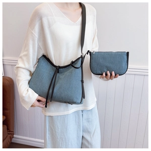 Close-up of denim tote bag with leather straps and matching small zipper pouch