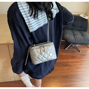 Detail view of silver quilted crossbody bag with metal rivets and chain strap on a model