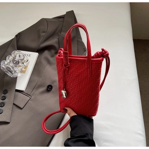 Détail du mini sac seau tressé rouge avec breloque argentée et bandoulière assortie