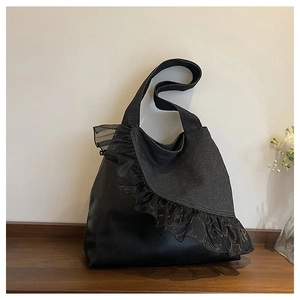 Close-up of black denim tote bag featuring elegant lace ruffles and patchwork design