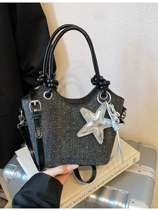 Chic dark denim tote bag with silver studs and a metallic star charm on books