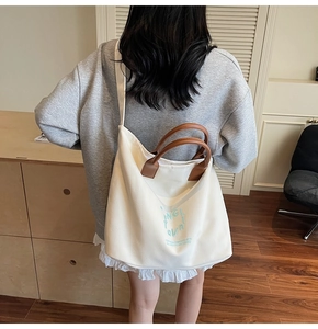 Gros plan d'un sac fourre-tout en toile blanche avec anses brunes et texte bleu design