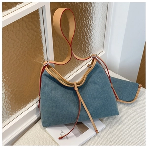 Detail of blue denim tote bag with tan leather straps and matching mini pouch accessory
