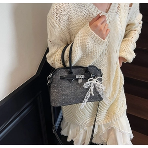 Détail du sac à bandoulière en denim avec nœud en dentelle blanche et cadenas argenté