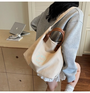 Détail du grand sac cabas en toile blanc cassé avec poignées en cuir marron et broderie