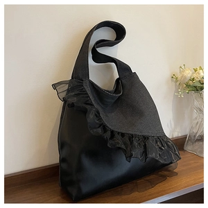 Detail of denim tote bag with black faux leather and sheer lace ruffles on a shelf