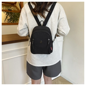 Detailansicht des schwarzen Mini-Rucksacks aus Nylon mit Reißverschluss an einem Frauenrücken