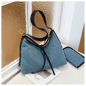 Detailed close-up of light blue denim tote with black leather trim and matching pouch