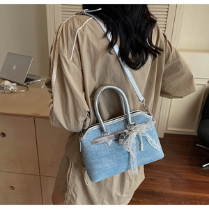 Détail du sac à main en denim bleu clair avec nœud en dentelle et perles argentées