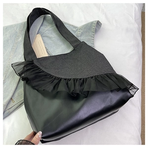 Detail of mixed denim and faux leather tote bag with elegant black organza ruffle trim