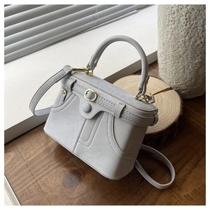 Detail of grey suede texture box bag with light gold hardware and neat stitching