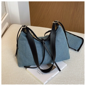 Detail of denim tote bag with leather straps and matching small pouch on a soft fabric