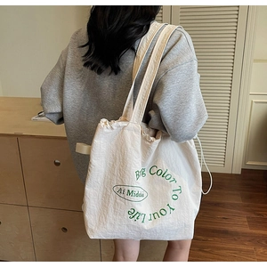 Detail of white canvas tote bag with green circular print and side drawstring closure