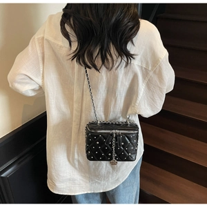 Rear view of model wearing a black quilted leather vanity bag with silver stud detailing