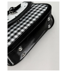 Detail of heart-shaped bag featuring plaid fabric, black faux leather and silver studs