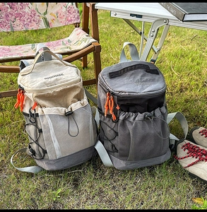 Outdoor backpacks with drawstring closure and orange zipper pulls on green grass