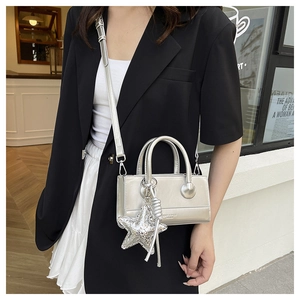 Detail of silver metallic crossbody bag with star charm and branding on black blazer