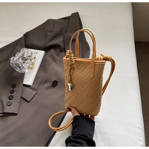 Détail d'un sac seau tissé avec texture marron et pendentif métallique élégant