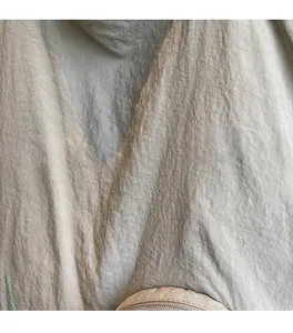 Detail of grey wrinkled fabric texture featuring a green cat outline and zipper closure