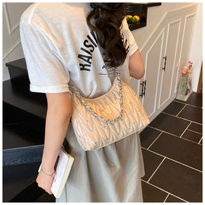 Nahaufnahme der beigen gesteppten Baguette-Tasche mit V-Nähten und silberner Kette