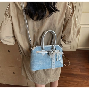 Détail du sac à main en denim bleu clair avec garniture argentée et nœud en dentelle