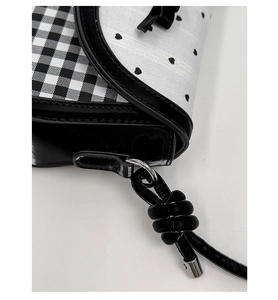 Close-up of black and white gingham flap bag with heart pattern and silver metal ring