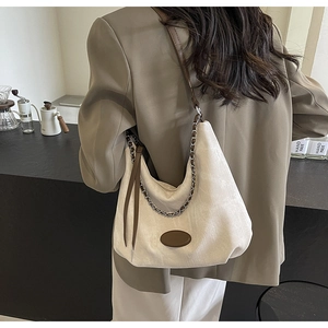 Detail of off-white canvas hobo bag with brown leather strap and woven chain accent