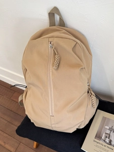 Minimalist beige nylon backpack featuring vertical front zipper and drawcord side pockets