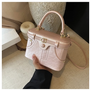 Detailed view of the pearlescent pink box bag with gold buckles and pleated leather