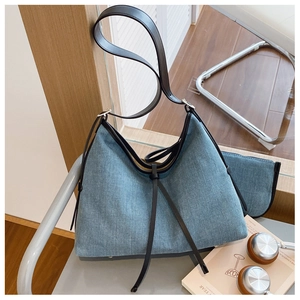 Detail of denim tote bag with leather straps and matching zip pouch on a chair