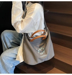 Détail du sac fourre-tout en toile gris foncé avec poignées en cuir et logo