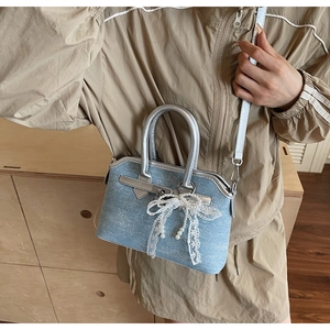 Détail du mini sac en denim bleu clair avec boucles argentées et nœud en dentelle
