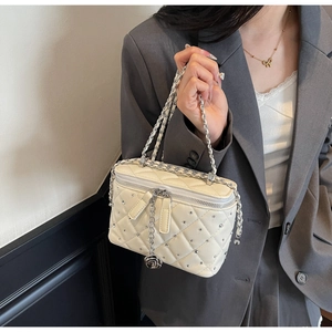 Close-up of diamond-studded cream quilted crossbody bag with camellia charm detail