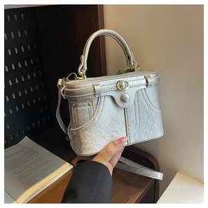 Detail of silver metallic box bag with vintage pleats, denim stitching and metal button