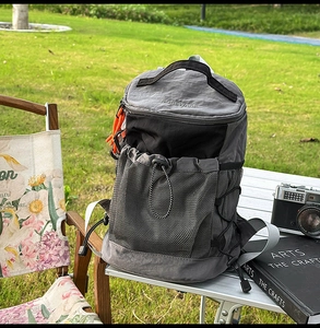 Detail of outdoor hiking backpack with gray nylon fabric, mesh pocket, and orange zipper pulls