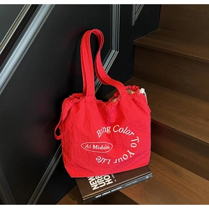 Detail of red nylon tote bag with drawstring closure on dark wooden steps