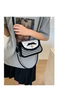 Detail of crossbody bag with heart print flap, black bow, and gold heart pendant charm