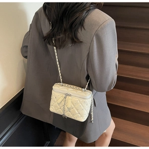 Detail of cream quilted lattice box bag with rhinestone studs and chain strap shown on model